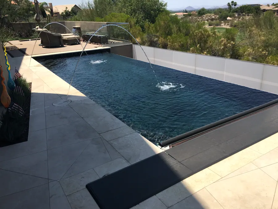 Long pool with two arcing water features and desert shrubs