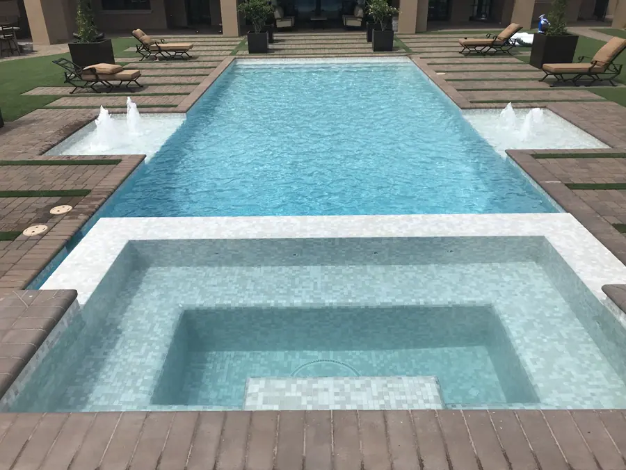 Square spa in front of a rectangular pool with paired fountains