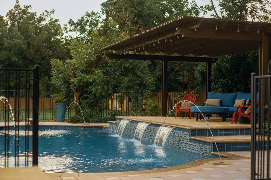 Pool water wall beside a shaded outdoor seating area