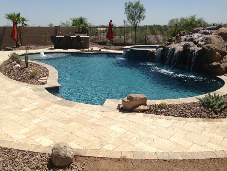 Freeform pool with a large rock waterfall and light stone deck