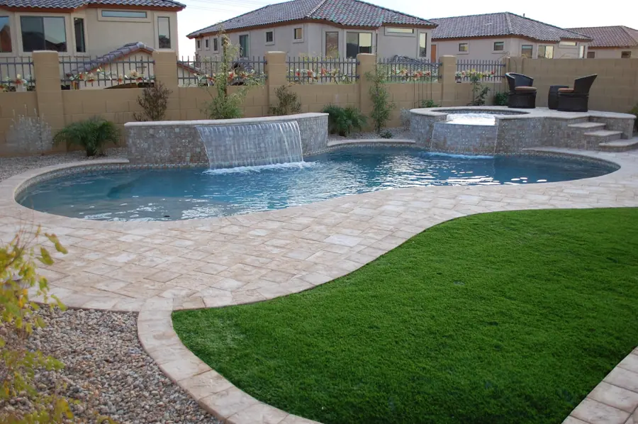 Freeform pool with a broad water wall and green lawn