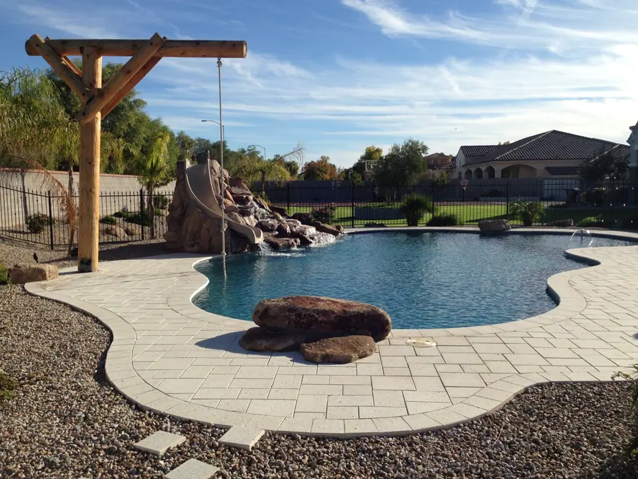 Curved pool with a rock slide and a wooden pergola