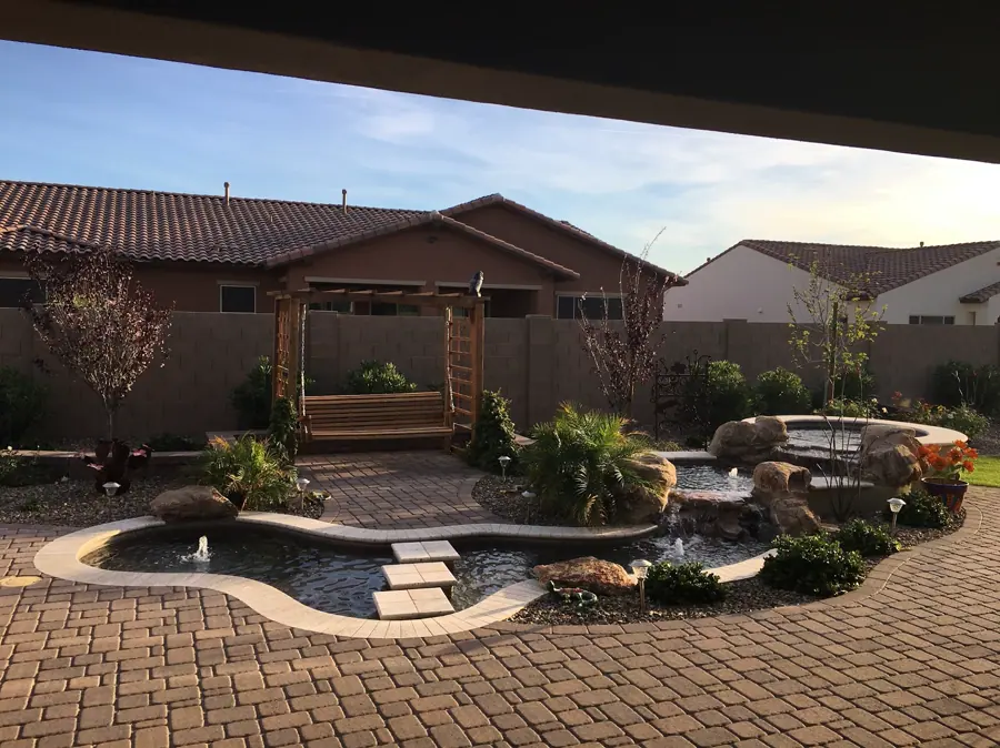 Landscaped yard with a curved pool and shaded seating