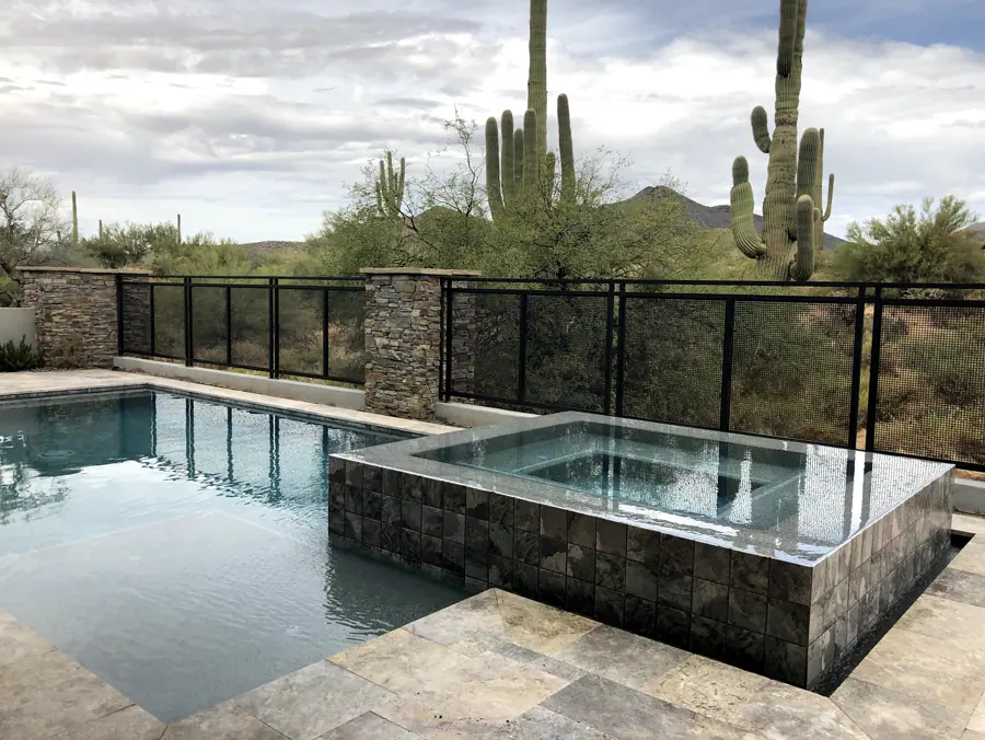 Rectangular pool and raised stone spa beside desert landscaping
