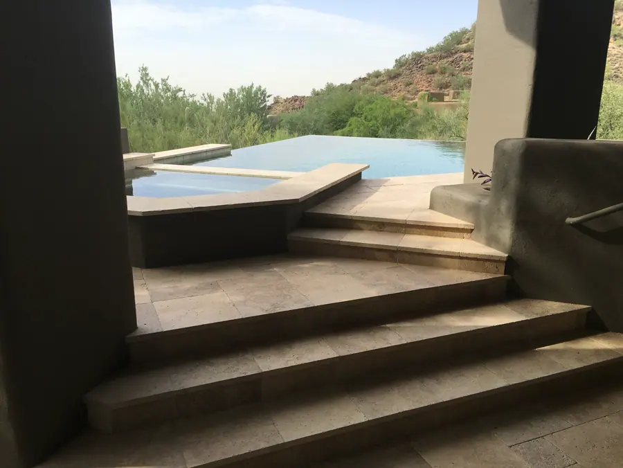 View through an open living space toward a pool and raised spa